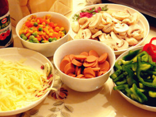 1、土司小披萨,青红椒切丝，火腿肠切片；口蘑切片、胡萝卜切丁与豌豆、玉米粒一起用开水焯一下