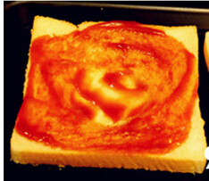 2、土司小披萨,将吐司片中间压出一凹坑，均匀涂上一层番茄酱