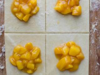 4、黄桃波旁威士忌红糖派,将煤气灶预热到180度，在工作台表面撒入大量面粉，将一个圆饼切成两半并将剩下的放入冰箱，将面团揉成长方形大约1厘米厚，把粗糙的边缘削减一下，用披萨刀将面团剪成8厘米.