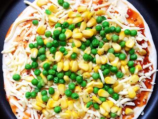 1、海鲜披萨,披萨饼头天晚上放到冷藏自然化冻，早上烤箱预热,涂披萨酱，再放奶酪再放豌豆和玉米。豌豆玉米烫熟沥干水份后使用。