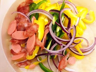 4、DIY亲子披萨,将三色辣椒和洋葱分别切丝。再将火腿肠和腊肠分别切成薄厚均匀的火腿肠片和腊肠片。