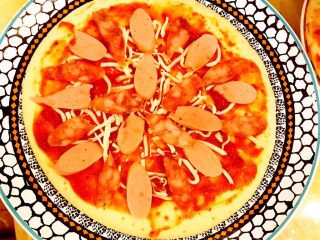 8、DIY亲子披萨,接着，分别铺放适量腊肠片和火腿肠片。