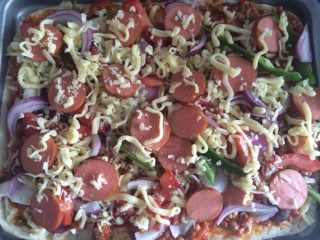 4、烤肠披萨,把炒好的酱涂到饼上撒、香菇片、洋葱、青椒、番茄片、撒马苏里拉奶酪、放烤肠片再撒一层马苏里拉奶酪