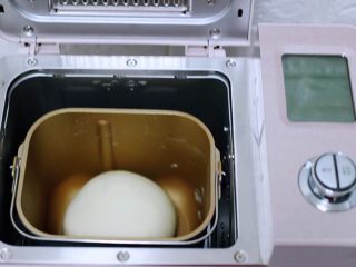 2、培根青豆披萨,启动面包机的一个和面程序后，用手把面团揉圆，再次放入面包机里进行醒发。