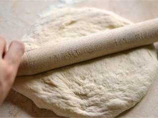 2、玛格丽特披萨,用手把披萨饼底面团 粗略整成呈一个圆形，然后用擀面杖擀开。