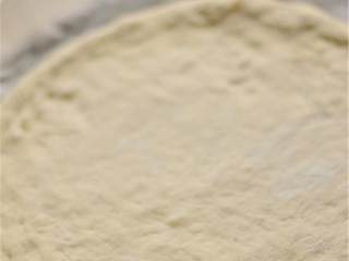 3、玛格丽特披萨,在案板上铺上一张烘焙纸，喷上油；把擀好的披萨饼皮放在烘焙纸上。