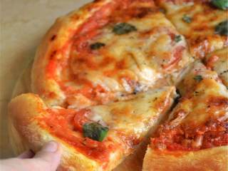 5、玛格丽特披萨,用案板把披萨和烘焙纸小心地转移到烤箱中预热好的烤盘上。出炉的时候戴好手套，小心地拉烘焙纸的一侧，带着披萨一起再转移回到案板上。