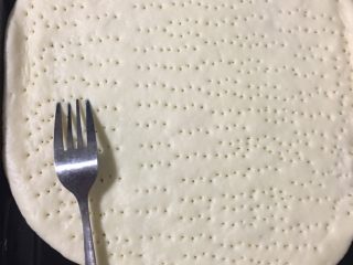 3、披萨,将发好的面团杆成圆形，再用叉子扎一些孔。放进烤箱烤3分钟左右，事先将烤箱先预热2分钟。