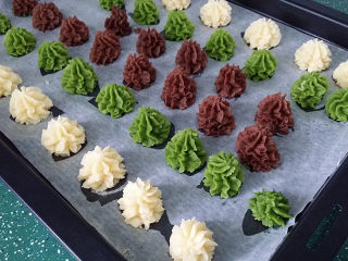 9、#网红甜品#网红三色曲奇,再分别挤入垫有油纸的烤盘中，同时以140度预热烤箱