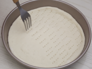 4、菠萝披萨,把饼坯放进烤盘，用叉子均匀地扎些洞