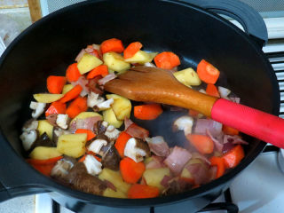 15、浓郁味香的【培根奶油炖菜】,土豆红萝卜块入锅翻炒，再加入香菇炒至半熟