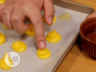 16、让世上没有难做的泡芙,都挤好后，在手指上沾一点水，把立尖的面团轻轻抹平，都抹好后就可以进烤箱了