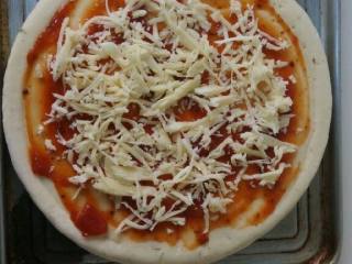 1、懒人版培根披萨,披萨饼肧抹上披萨酱，均匀的撒上一层奶酪丝