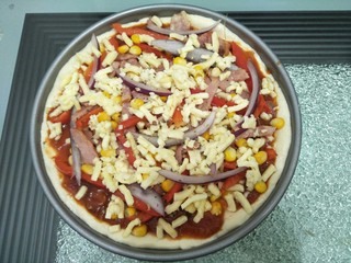 11、培根蔬菜披萨,放入煮好的蕃茄酱料，再放入马苏里拉，放入培根，洋葱，玉米最后铺上马苏里拉芝士，放入预热好的160度烤箱烤25分钟。