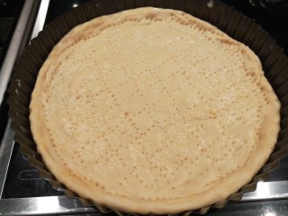 5、新文美食  自制烤箱板披萨,放入一块面团用手压扁，最压成披萨饼披，用钢叉扎上均匀的孔。