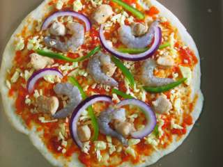 9、鲜虾鸡肉披萨,把鸡肉、虾仁、洋葱丝和青椒丝依次放在饼皮上