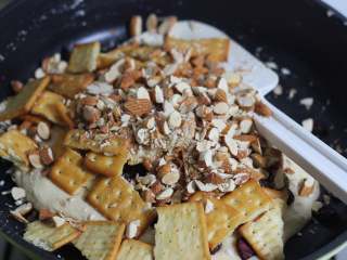 5、雪花酥,倒入蔓越莓干，巴旦木，苏打饼干，然后就关火，避免火大烧焦了糖！翻拌，尽量让棉花糖和饼干坚果混合到一起