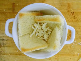 7、吐司披萨盏,把吐司片摆入烤碗中，没有烤碗的也可用纸杯。然后撒少许马苏里拉芝士碎。