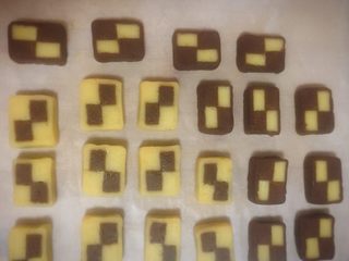 18、双色格子/棋盘饼干,同样的方法也把可可面团的边角料包裹格子条,切成片。还有一条格子条直接切片。把切片都放在铺了油纸的烤盘上