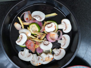 7、柠檬香辣烤冰鱼,将刚刚用来腌鱼的洋葱、生姜、口蘑、柠檬片全部铺在烤盘中。