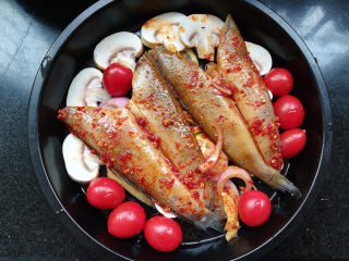 8、柠檬香辣烤冰鱼,将鱼摆放在蔬菜上面，倒入腌鱼的汤汁。摆上几个千禧。