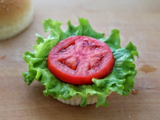 13、芝士肉排汉堡,将汉堡胚切成两半分别抹上沙拉酱，在下层铺上生菜叶和切片的西红柿