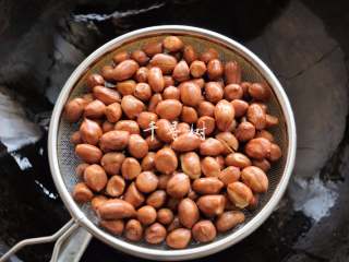 5、香酥油炸花生米,仔细看的话，花生米的外皮颜色和生花生米已经不一样了，稍微有些变暗了，并且密集的噼啪声已经消失，个别的花生米外衣也炸裂了，这个时候就可以捞出来控油了。花生捞出来之后的余热也会继续加热花生，所以如果等到花生米明显变色再捞的话就意味着炸过头了。