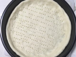 5、火腿鸡肉披萨,发酵好的面团,揉一会,擀成饼皮,边厚一点,放入烤盘,用叉子扎孔