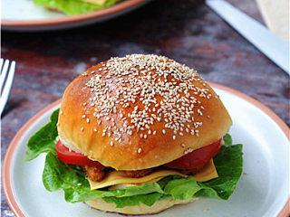 12、炸鸡芝士汉堡,将炸鸡块摆在上面，再放上西红柿块，盖上面包片，组合好即可。