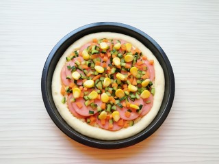 9、火腿彩蔬披萨,均匀的撒上黄瓜丁、胡萝卜丁和熟玉米粒。
