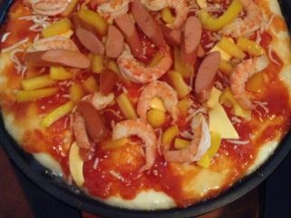 4、饼铛披萨,把发好的面擀好，饼铛锅加热放油，擀好的面放在饼锅上先抹上制作好的番茄酱，洒上一层乳酪，芝士，把剩下的料全摆上，大概八分钟就可以出锅了