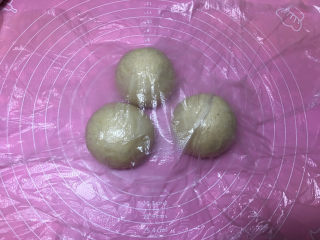 5、燕麦辫子花环汉堡面包,将面团取出进行排气，然后平均分成三份，滚圆后盖保鲜膜醒发15分钟。