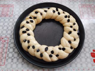 11、圣诞花环面包,面团转入12寸披萨盘中。烤箱发酵30分钟，取出放上黑加仑装饰，刷一层薄的蛋液，同时预热烤箱160度