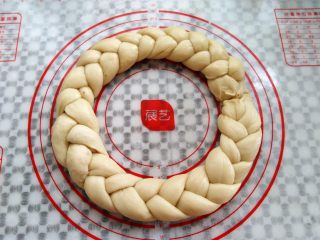 10、圣诞花环面包,另外三根面条接到编好的面团后面，六根面条编成一个圆形，首尾接缝处捏紧（觉得麻烦的可以做2个小的花环）