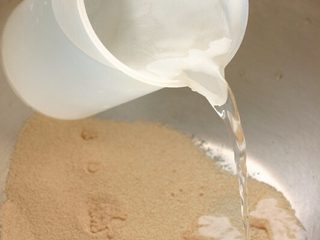 1、素食披萨,酵母粉倒入30°C开水中搅拌均匀备用。