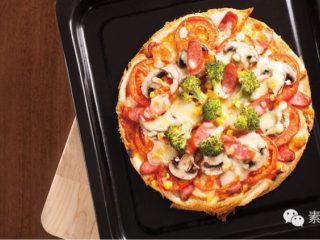 3、素食披萨,将烤盘放入已经预热的烤箱。 以上下火180°C烤10分鐘，至披萨