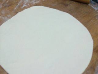 3、微波炉版披萨,把面团的气泡揉挤掉，擀成比烤盘稍大的薄圆饼