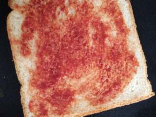 1、土司披萨#健康美颜餐#,将土司一面均匀的抹上番茄酱