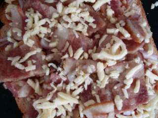 3、土司披萨#健康美颜餐#,将培根均匀的铺在洋葱上，在撒上马苏里拉奶酪碎