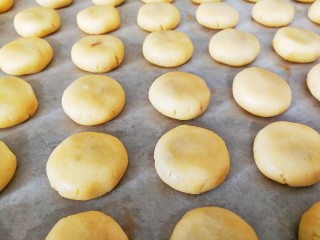 10、咸蛋黄肉松一口酥,依次全部做好，放在垫好油纸的烤盘上，然后逐一轻轻压扁，预热烤箱，上下火175度十分钟左右