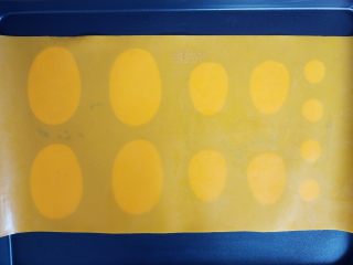 5、抹茶仙人掌马卡龙,按照设想的大小，将纸折叠后剪成大小一致的纸片，放在硅胶垫和烤盘之间