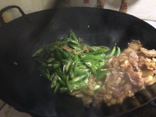 5、农家小炒肉 湘菜,把上好色的肉拨到一旁，辣椒入锅。开始翻炒。看到辣椒慢慢熟了，加大葱段。再次翻炒。