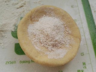 7、芝麻玉米面白糖饼,取一个面剂，擀成边薄里厚的圆片，放白糖馅(我是两手转圈把边捏薄，习惯了。)