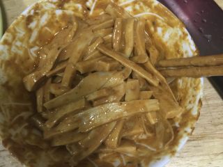 5、手撕杏鲍菇,把杏鲍菇条放入调好的酱汁里，搅拌均匀，装盘，点缀红色辣椒圈。