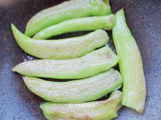 3、虎皮青椒,小火慢炕,一边炕一边用勺子按压青椒,炕的时候要经常翻动青椒,避免青椒单面炕糊,部分青椒已起虎皮,要将没有起虎皮的青椒炕到。当虎皮已起,青椒已完全变软,盛出备用。