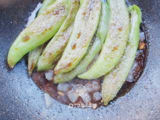 5、虎皮青椒,放入刚刚炕好的虎皮青椒一起翻炒,在小碗里倒两勺半生抽、一勺醋、少许盐、一勺半糖,再倒入一些清水,调制好酱汁,倒入锅中,大火翻炒几下后出锅