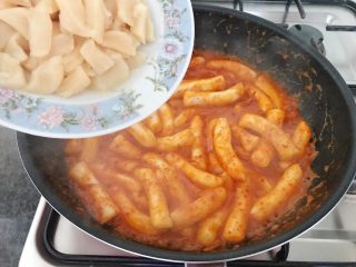 14、芝士辣烤年糕,等年糕有点粘稠时把鲜贝加进来，这个时候要顺时针不停的搅拌，直至年糕变软，水要几乎收干，关火。