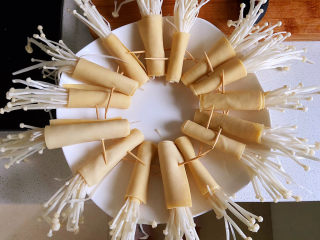 4、豆皮金针菇卷,包住以后用牙签固定,不然放进锅中就会散开。