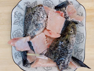 3、家庭水煮鱼,鱼骨另外用一个碟装好，也加入料酒和姜腌制去腥。