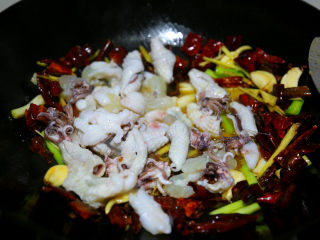 12、麻辣鲜香小鱿鱼,灼好的鱿鱼下锅了,加少许料酒大火炒30秒左右。